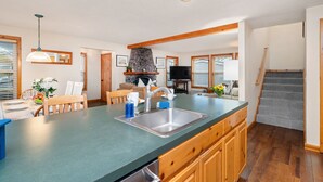 A modern kitchen with a large island, wooden cabinets, and a stone fireplace. - Treasure Paradise MCA#522-Only 1 1/2 blocks to the beach. Close to everything (Manzanita)