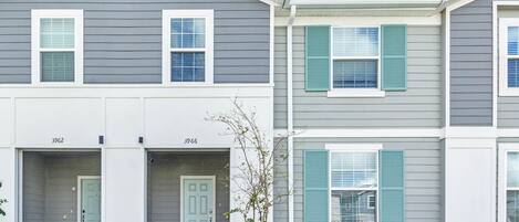 A row of townhouses with grey siding and white trim, numbered 3962 and 3966, featuring front porches and shutters.