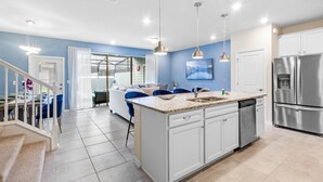 A modern kitchen with white cabinets, a stainless steel refrigerator, and a granite countertop. - Relaxing 5 Bed Townhome with Splash Pool-3966LA (Davenport)