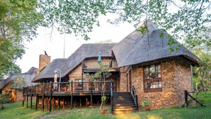 A thatched-roof house with a wooden deck and brick walls. - Kruger Park Lodge Unit No. 205 (Mbombela)