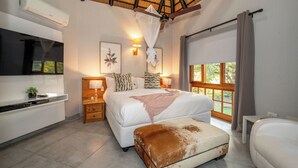 A bedroom with a large bed, bedside tables, a TV, and a window with curtains. - Kruger Park Lodge Unit No. 205 (Mbombela)