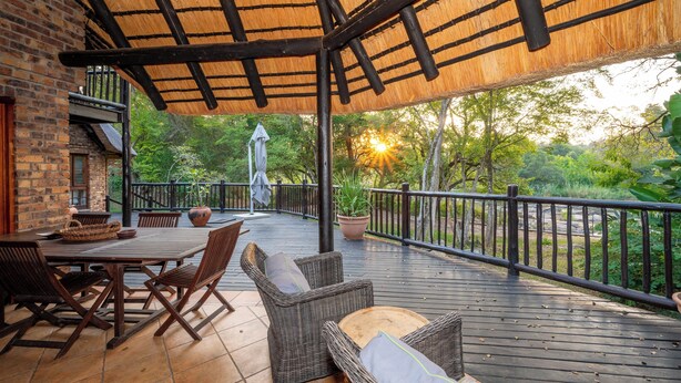An outdoor patio with a wooden deck, wicker furniture, and a thatched roof structure. - Kruger Park Lodge Unit No. 205 (Mbombela)