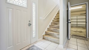 A staircase leading to a second floor, a white door with a glass panel, and a garage door.