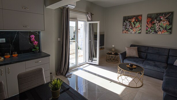 A modern living room with a sofa, a coffee table, and a kitchen area with a TV.