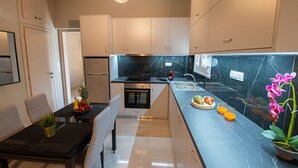 A modern kitchen with a marble countertop, built-in oven, and a dining area with a table and chairs.