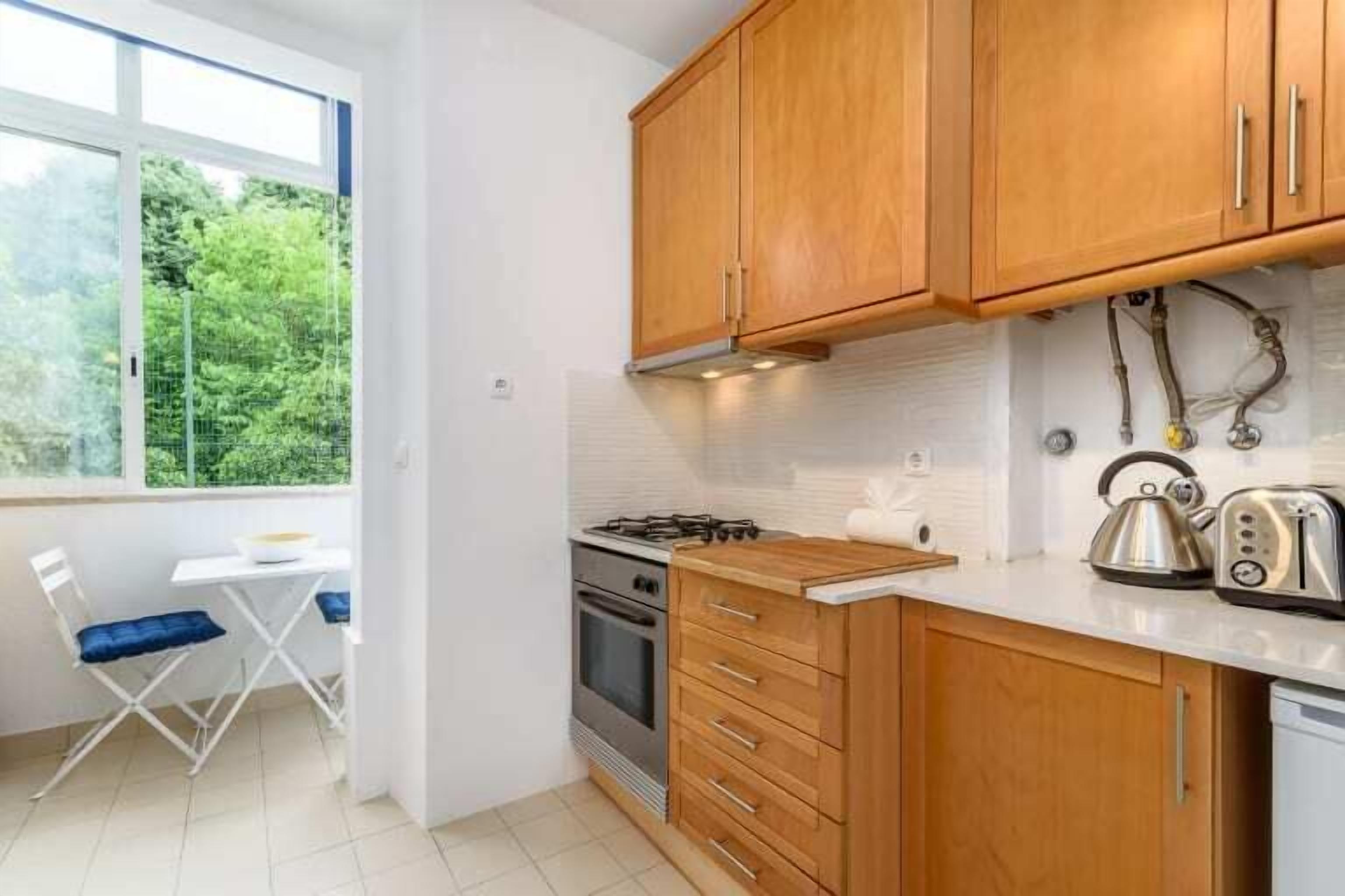 Une cuisine compacte avec des meubles en bois, une cuisinière à gaz, une bouilloire et un grille-pain.