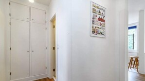 A hallway with a white wardrobe, a framed poster on the wall, and a wooden floor.