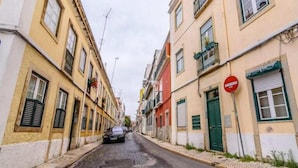 A narrow street lined with buildings, a no entry sign, and a parked car.