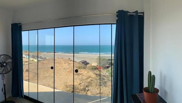 A room with a large sliding glass door leading to a beach view. - Deluxe Double Room with Balcony and Sea View (Pis Lobitos)
