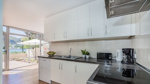 A modern kitchen with white cabinets, a stainless steel sink, and a coffee maker. - Sunset Villa Isleta (Alcúdia)