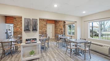 A spacious indoor area with wooden flooring, stone walls, and multiple tables and chairs.