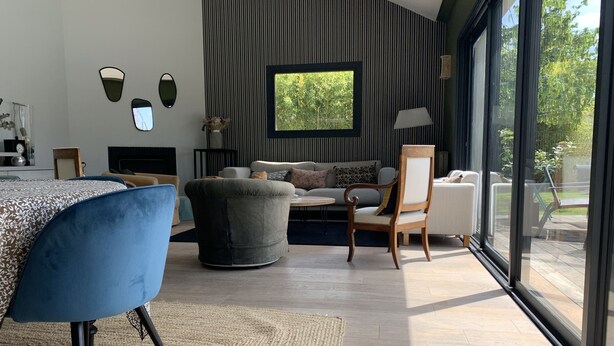 Uma sala de estar moderna com sofá, poltronas e um espaço de jantar com mesa e cadeiras.