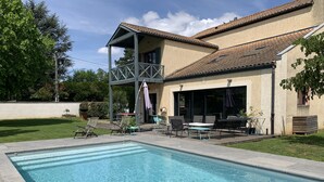 Piscina com área de terraço, móveis de exterior e espaço coberto para sentar.