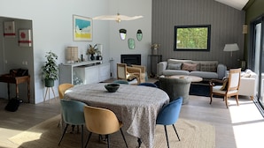 Uma sala de estar moderna com área de jantar, um conjunto de sofás e lareira.
