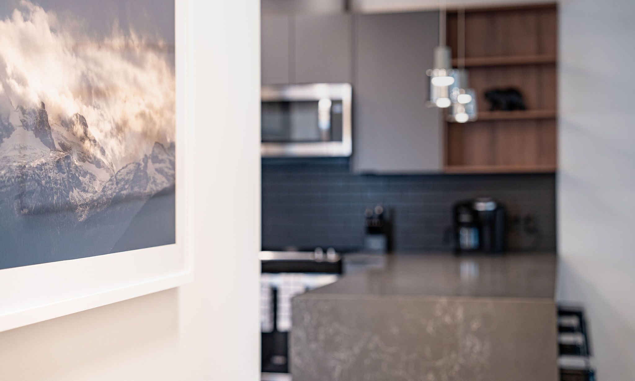 Een moderne keuken met een magnetron, koffiezetapparaat en hanglampen.