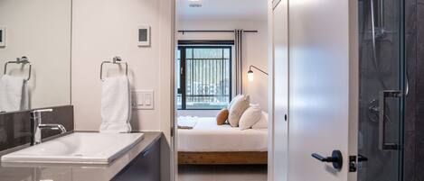 A modern bathroom with a large mirror, a white sink, and a glass shower enclosure.