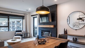 A modern dining area with a wooden table, black chairs, and a hanging pendant light. - Altitude Adjustment Revelstoke Vacations (Revelstoke)