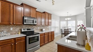 A modern kitchen with wooden cabinets, stainless steel appliances, and a white countertop. - Equine Escape - 3BR - BBQ Grill - 2-Car Garage (Lexington)