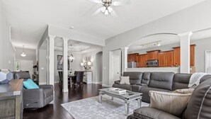 A spacious living room with a dark wood floor, a leather sofa, a glass coffee table, and a ceiling fan. - Equine Escape - 3BR - BBQ Grill - 2-Car Garage (Lexington)
