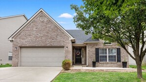 A single-story brick house with a garage, a front door with a wreath, and a small tree in the front yard. - Equine Escape - 3BR - BBQ Grill - 2-Car Garage (Lexington)