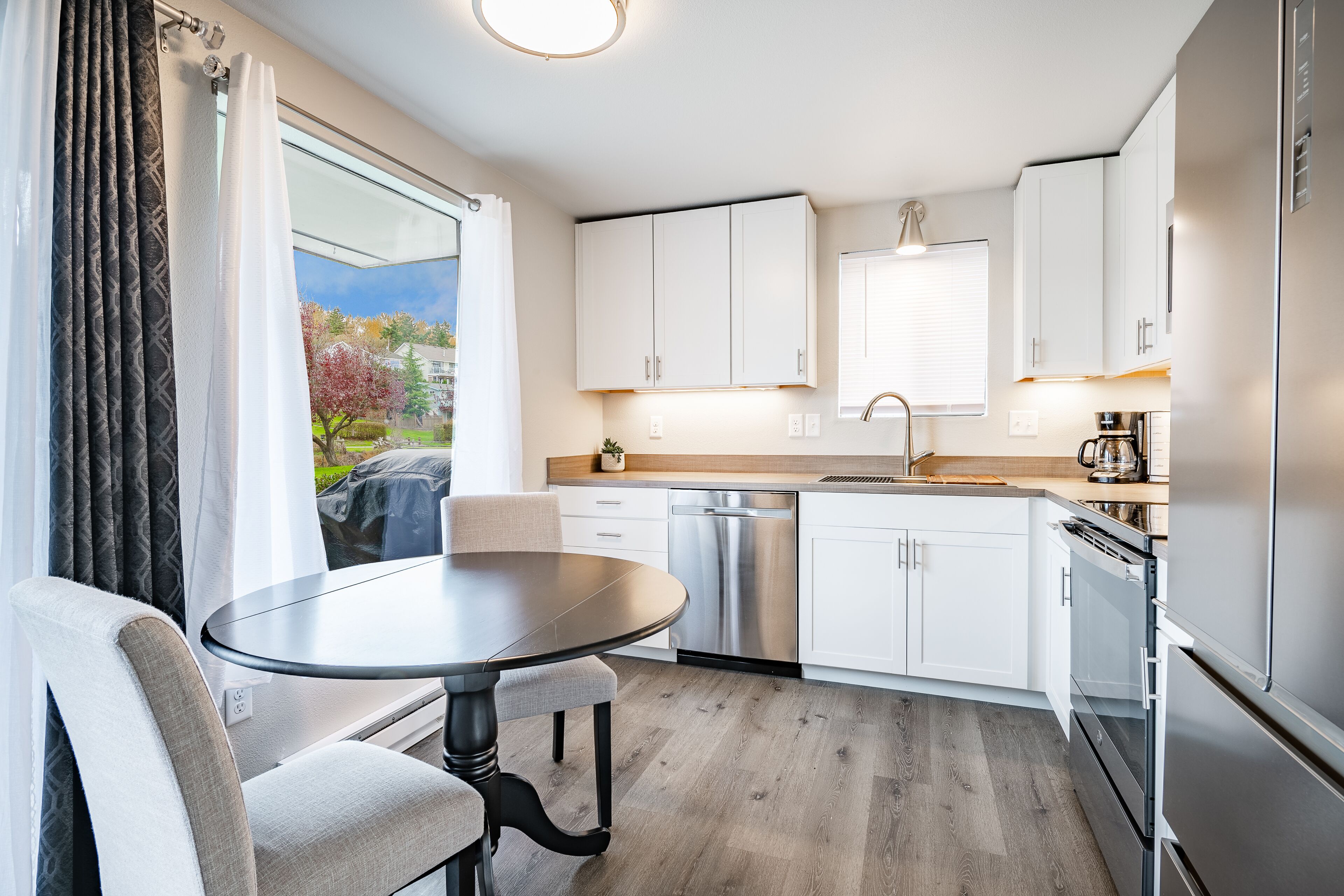 A modern kitchen with white cabinets, a stainless steel dishwasher, and a built-in oven.