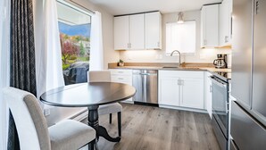 A modern kitchen with white cabinets, a stainless steel dishwasher, and a built-in oven.