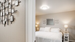 A bedroom with a bed, bedside tables, a wall-mounted light fixture, and a mirror.