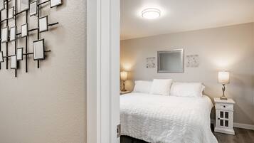 A bedroom with a bed, bedside tables, a wall-mounted light fixture, and a mirror.