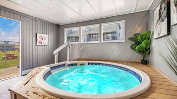Un jacuzzi en una habitación con vistas a una casa, una escalera y una planta en maceta.