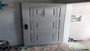 A white door with a keyhole and a handle, a tiled floor, and a shelf with books and a blue object.