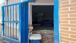 A blue metal gate leading to a building with a tiled entrance and a trash bin.