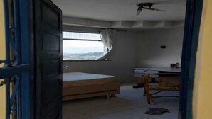 A bedroom with a bed, a desk, and a window with curtains.