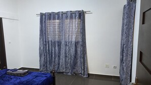 A bedroom with a bed, a curtain, and a door. - Cozyapartment (Cotonou)