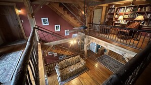 A wooden interior with a staircase, a sofa, and a bookshelf. - The Henhouse at The Yellow Barn Estate (Freeville)