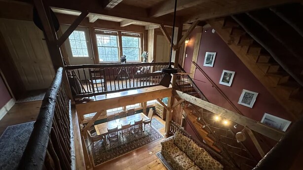 A spacious loft-style interior with a wooden staircase, a dining area, and a cozy seating area. - The Henhouse at The Yellow Barn Estate (Freeville)