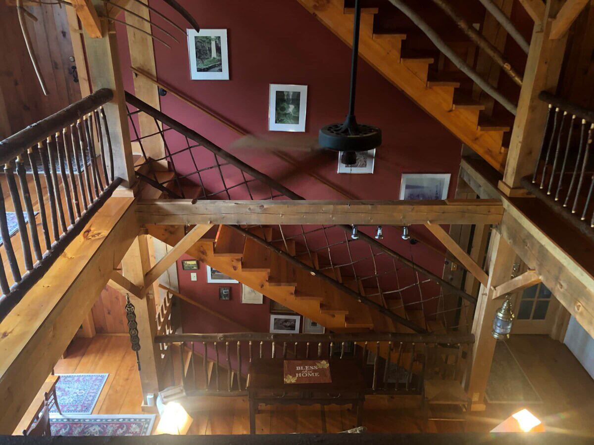 Una scala in legno con una parete rossa e quadri appesi.