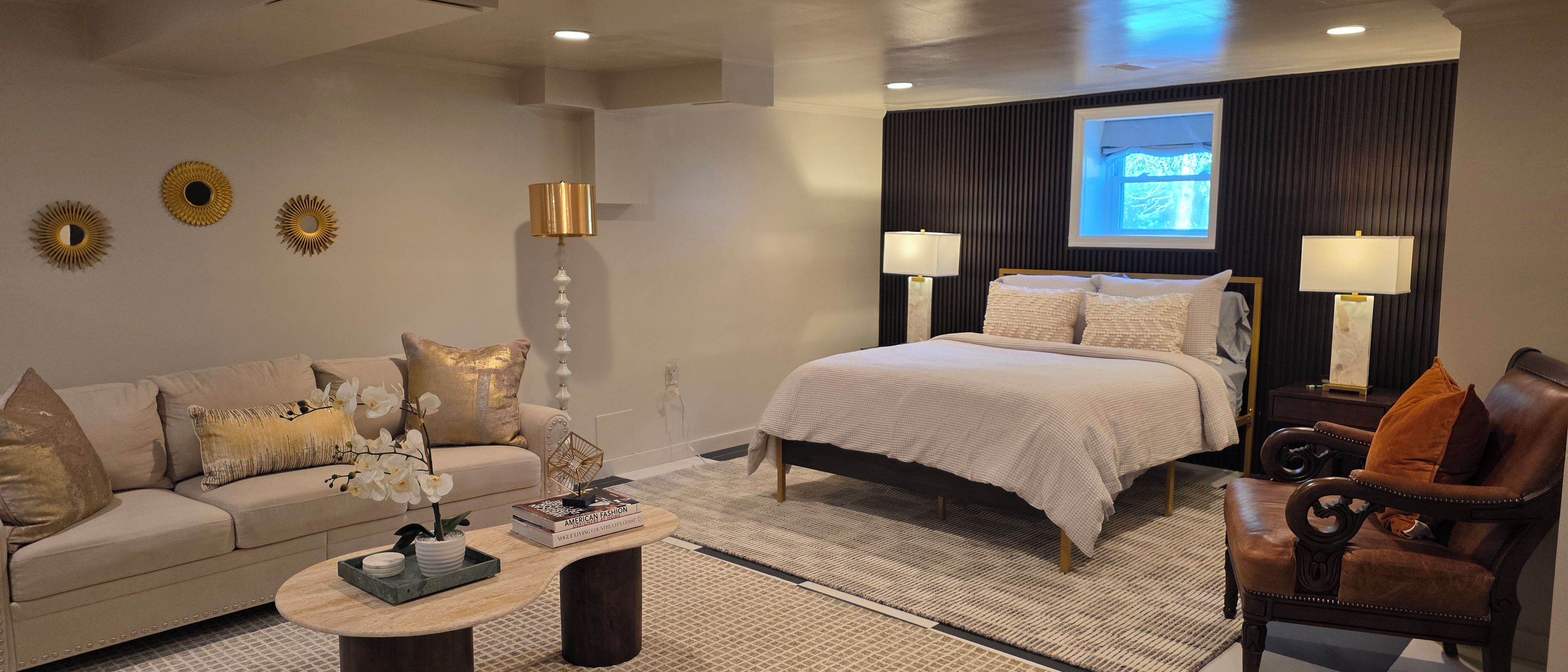 A hotel room with a bed, a sofa, a coffee table, and a chair.