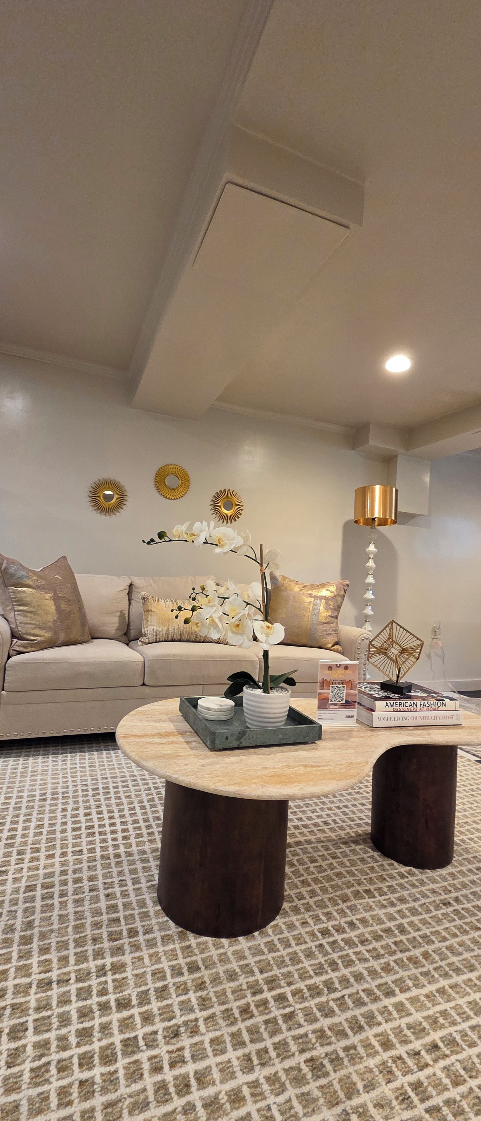 Een moderne woonkamer met een bank, salontafel, decoratieve spiegels en een vloerlamp.