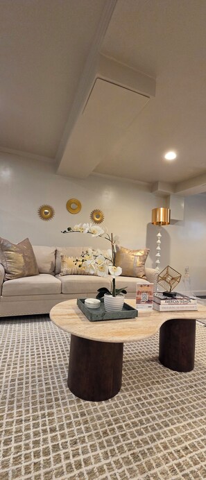 Una sala de estar moderna con sofá, mesa de centro, espejos decorativos y lámpara de pie.