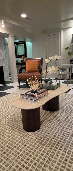 Una sala moderna con una mesa de centro de madera, un sillón de cuero y una planta de orquídea decorativa.