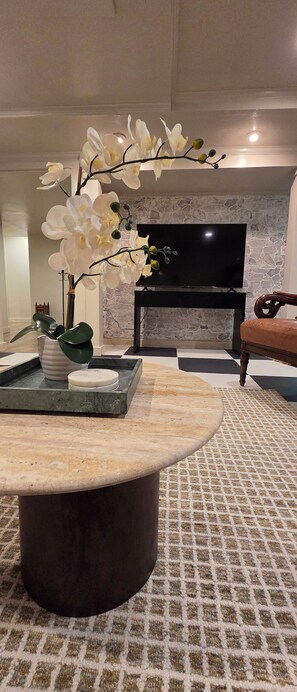 A living room with a stone fireplace, a flat-screen TV, a round coffee table, and a patterned carpet. - Clean/Comfortable/Spacious/Peaceful Outdoor Space

 (West Orange)