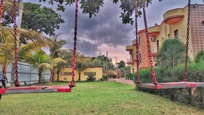 A residential area with a swing set, palm trees, and a building with a yellow facade. - The Sea Horse (Kanthi)