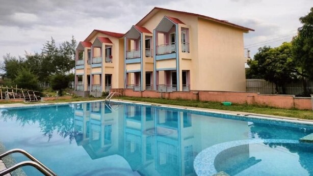 A multi-story hotel with a swimming pool in front. - The Sea Horse (Kanthi)
