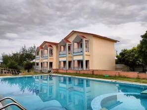 A multi-story hotel with a swimming pool in front. - The Sea Horse (Kanthi)