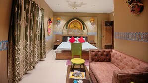 A hotel room with a bed, a sofa, a coffee table, and a decorative wall. - The Sea Horse (Kanthi)
