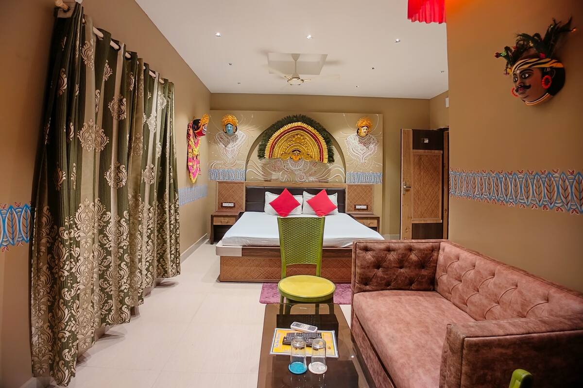 A hotel room with a bed, a sofa, a coffee table, and a decorative wall.