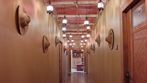 A hallway with patterned wall decorations, a wooden door on the right, and a visible room in the distance. - The Sea Horse (Kanthi)