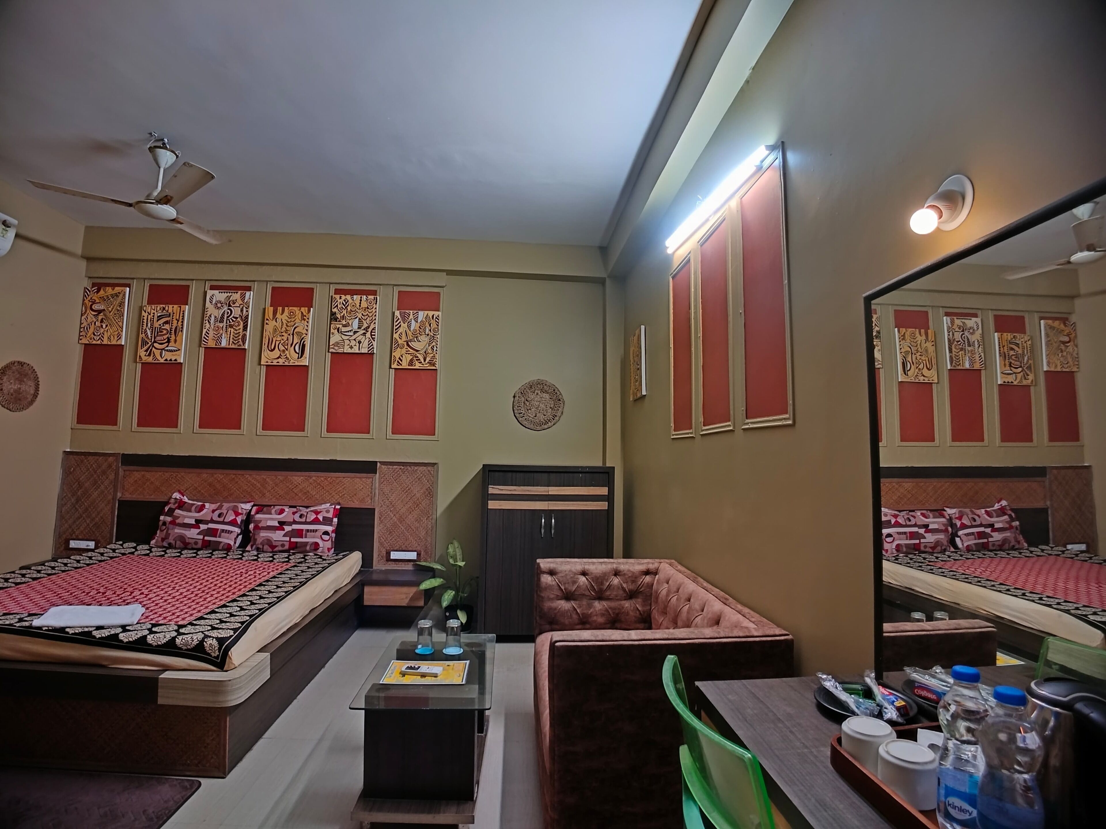 Habitación de hotel con dos camas, una zona de estar, un escritorio y un espejo.