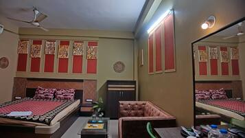 Habitación de hotel con dos camas, una zona de estar, un escritorio y un espejo.