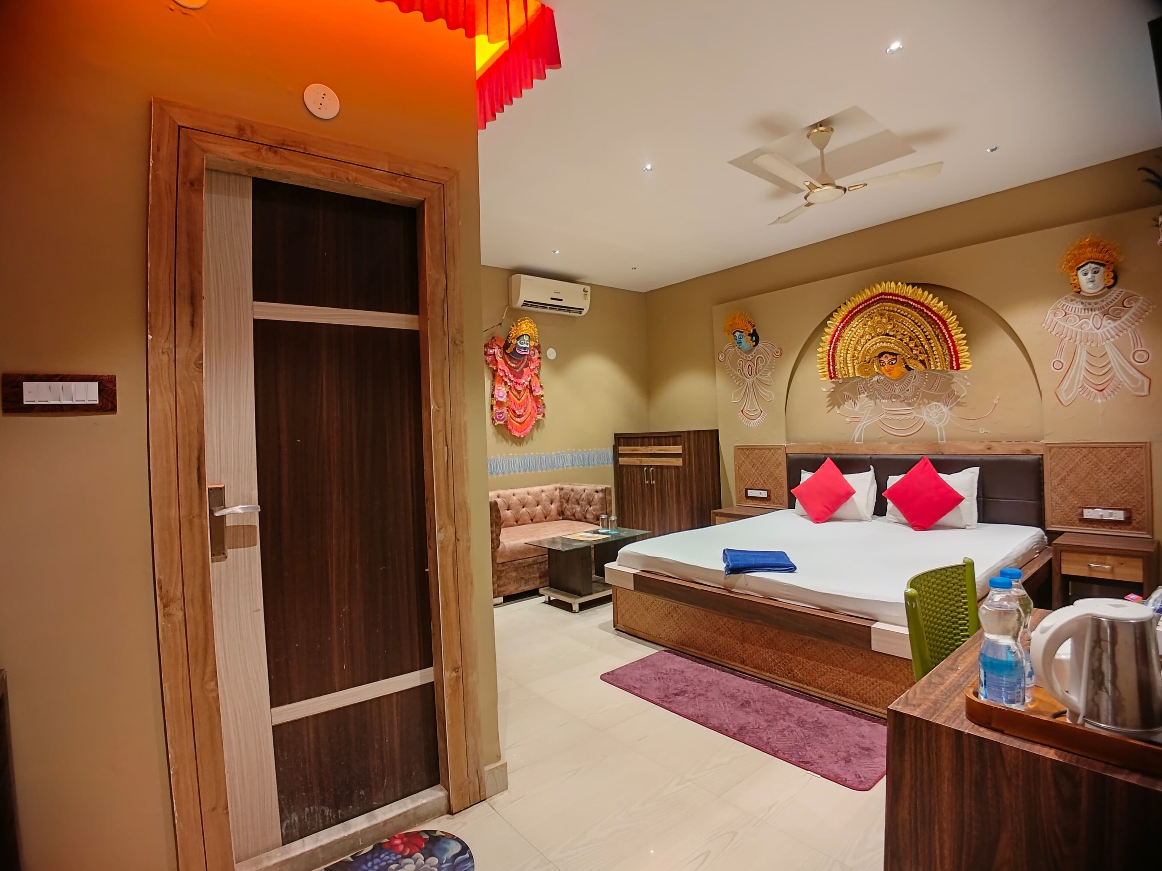 A hotel room with a bed, a desk, a chair, a wardrobe, and a ceiling fan.